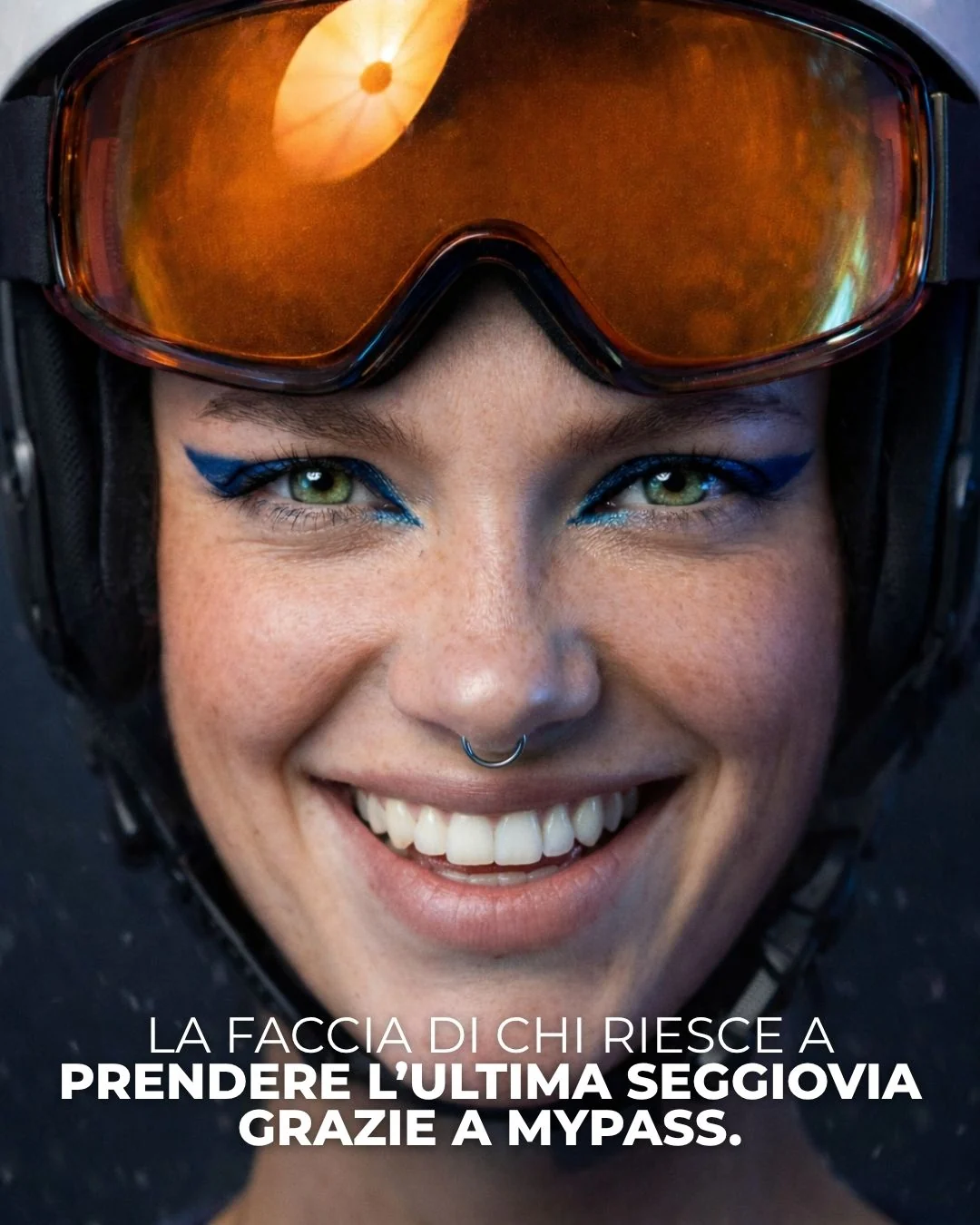 Ritratto ravvicinato di una sciatrice con casco e maschera arancione sulla fronte, lentiggini e sorriso, con la riga sulla seggiovia presa grazie a MyPass